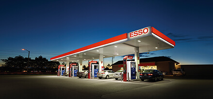 An Esso station at sunset with some cars